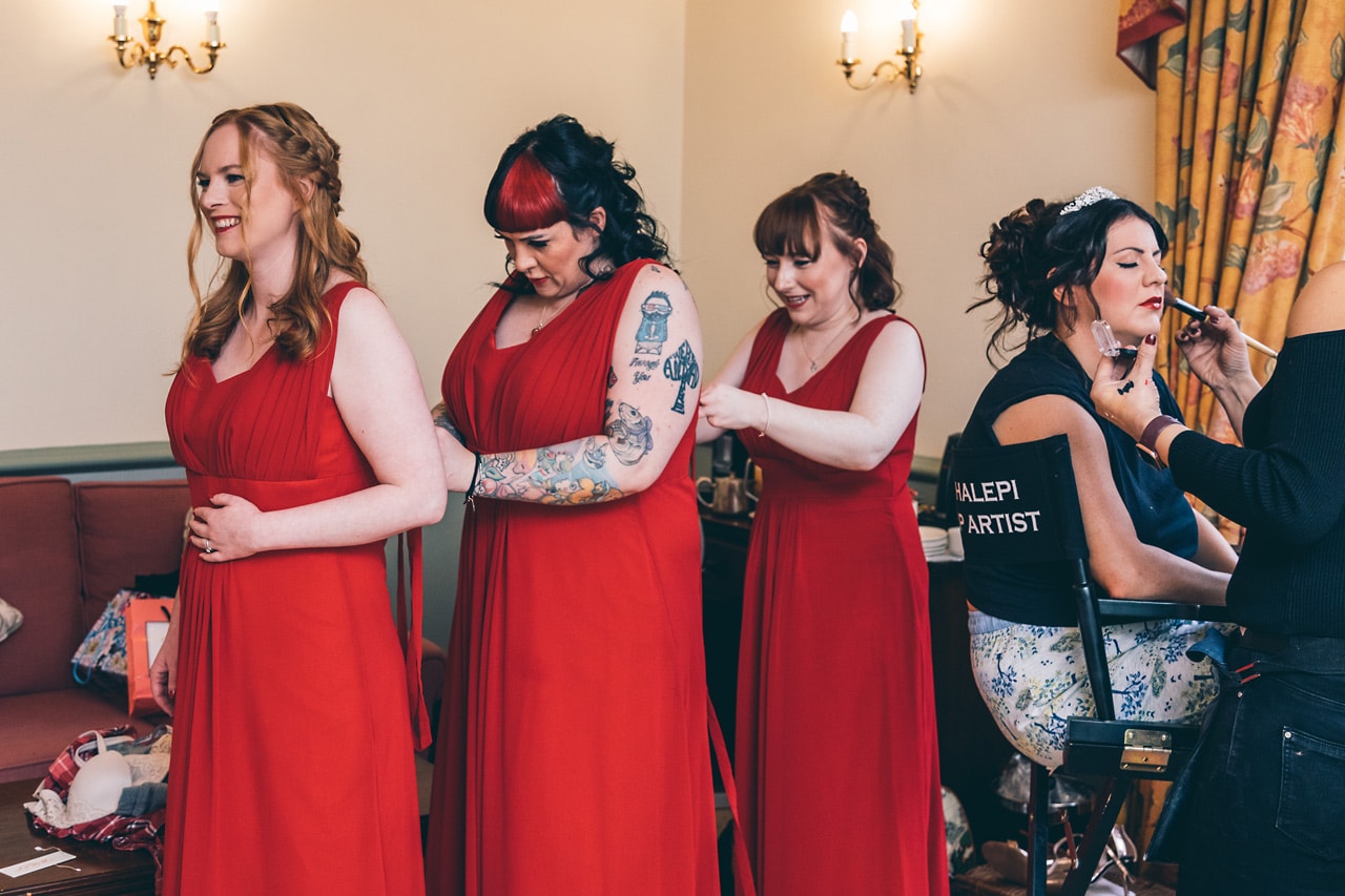 Bridesmaids helping each other into their dresses